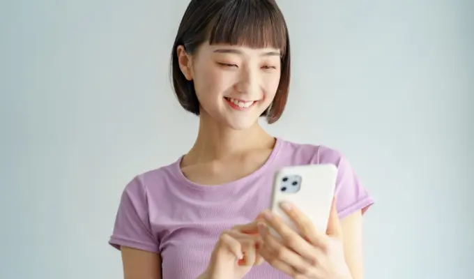 スマホで予約アプリを操作する笑顔の女性